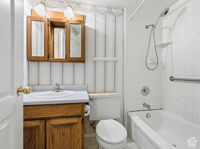 White ceramic tiled bath and shower combination with a grab bar