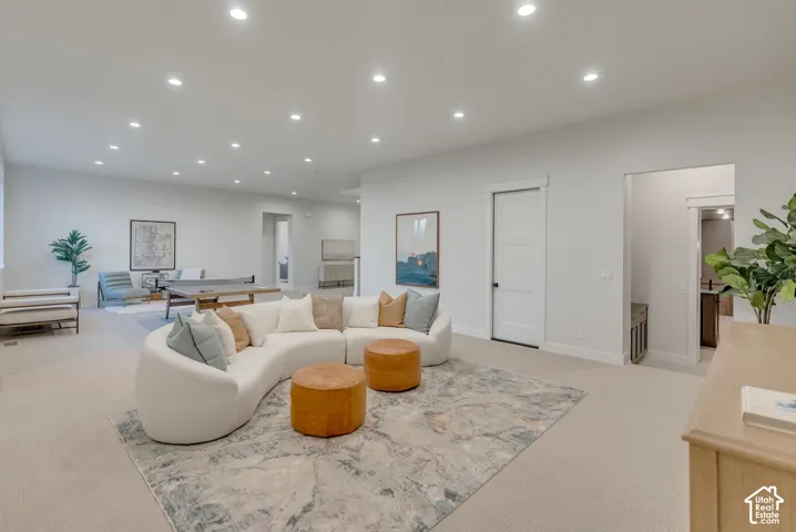 Expansive open-concept room featuring neutral wall-to-wall carpeting, recessed ceiling lighting, and solid-core interior doors with minimalist trim