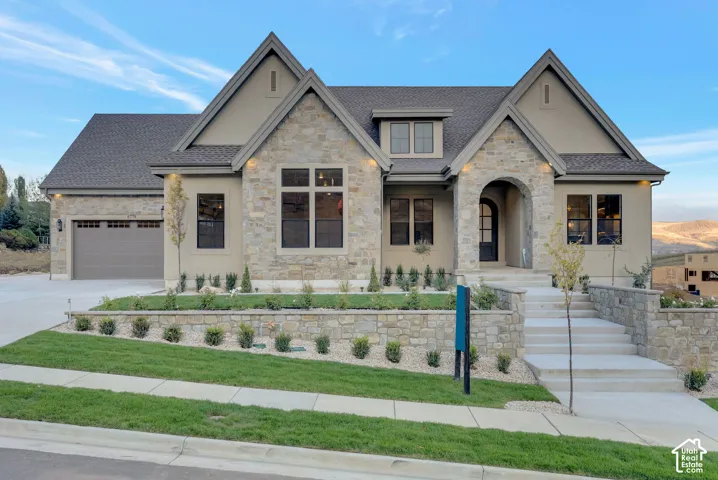 Exterior facade featuring stone veneer detailing, multi-gabled rooflines, an arched entryway, and concrete hardscaping