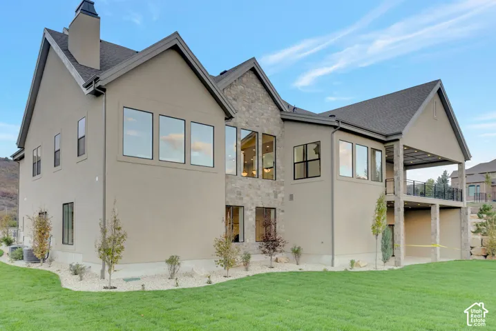 Multi-gabled exterior featuring stucco siding, stone veneer accents, multi-pane windows, and a covered rear deck
