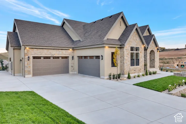 Multi-gabled exterior featuring stone veneer siding, stucco accents, an asphalt shingle roof, and a three-car garage
