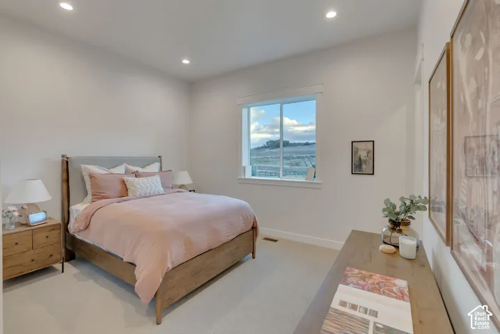 Neutral-toned interior space featuring recessed ceiling lighting, light-toned carpeting, and a large sliding window with an exterior landscape backdrop