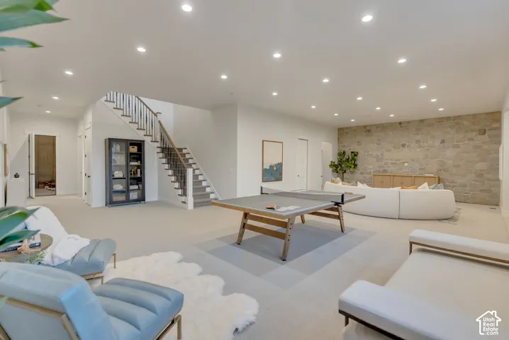 Expansive open-concept room featuring a textured stone accent wall, recessed lighting, and a staircase with metal balusters