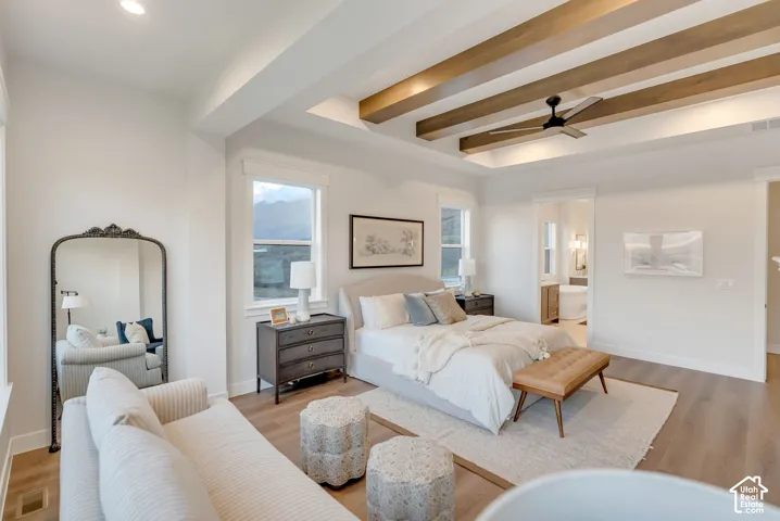 Tray ceiling featuring exposed wood-finish beams, recessed lighting, and a modern ceiling fan, complemented by wide-plank wood-finish flooring