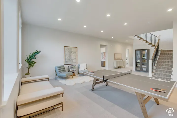 Open floor plan featuring recessed lighting, carpeted flooring, and a staircase with metal railings