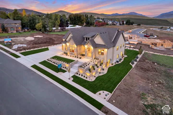 Multi-level residence featuring stone and stucco exterior, tiered retaining walls, concrete driveway, and mountain backdrop