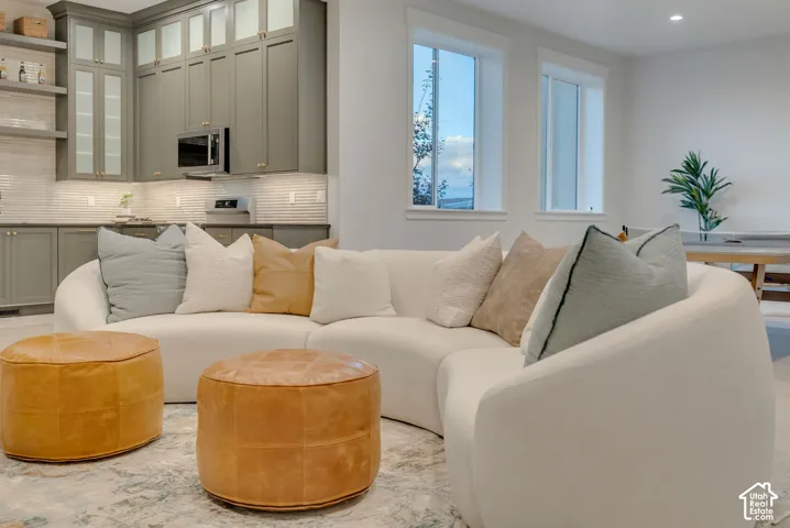 Custom cabinetry with integrated microwave, linear tile backsplash, open shelving, and tall windows