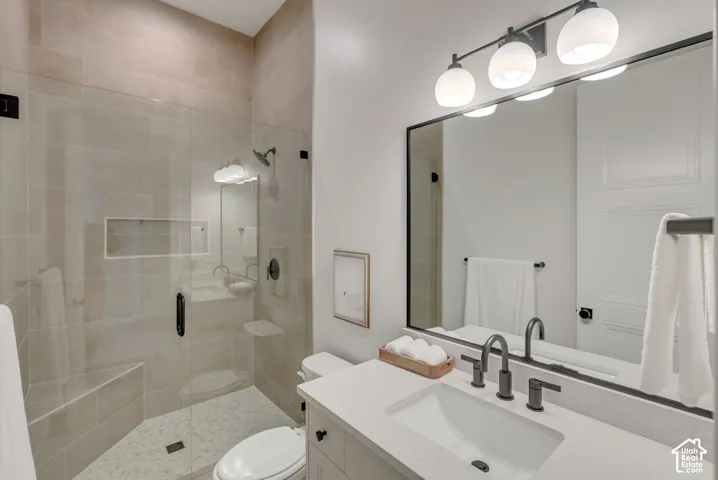 Bathroom featuring a walk-in shower with full-height tile surround, built-in bench, and frameless glass door, paired with a vanity topped in solid-surface material, undermount sink, and matte black hardware