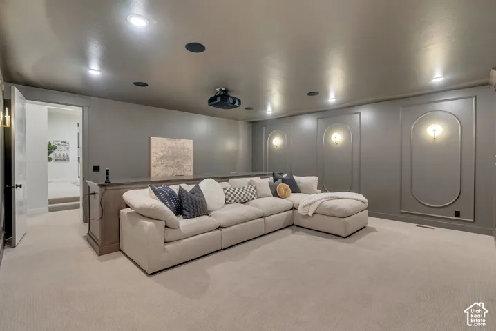 Neutral-toned room featuring arched wall molding, recessed ceiling lighting, wall-mounted sconces, and a ceiling-mounted projector