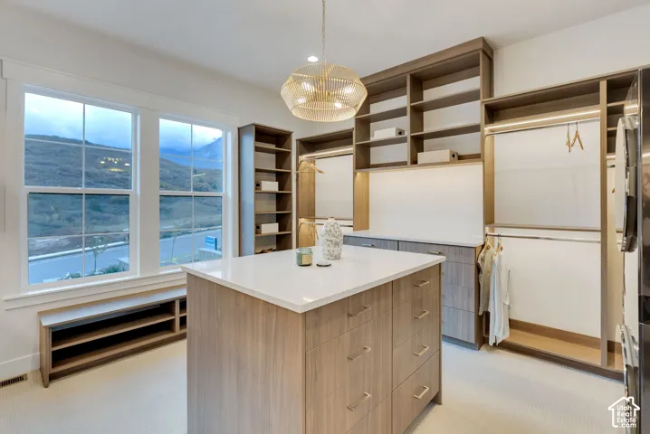 Custom closet featuring wood-finish cabinetry, a central island with a quartz countertop, integrated shelving, and large double-hung windows