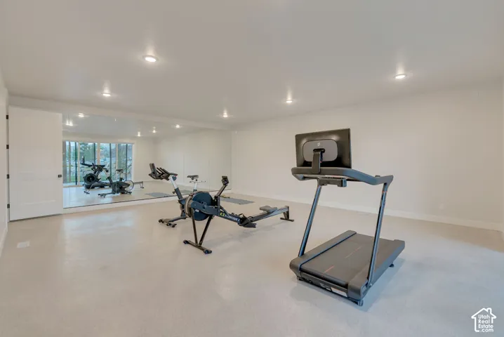 Expansive room featuring wall-to-wall mirror installation, neutral smooth-finish flooring, and recessed ceiling lighting