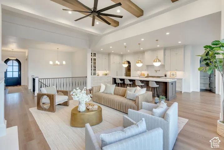 Open-concept area featuring exposed ceiling beams, wood-finish flooring, a kitchen island with stone countertop, coffered ceiling detail, and recessed lighting