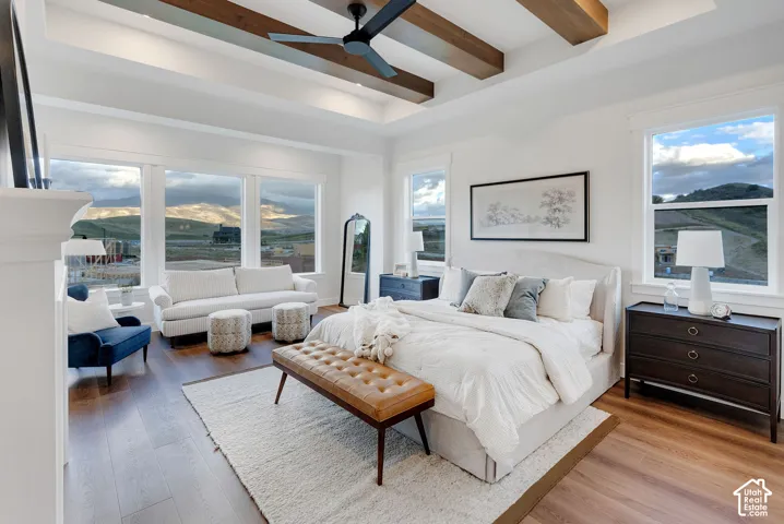 Tray ceiling with stained wood beams, wood-finish flooring, and large windows featuring mountain scenery
