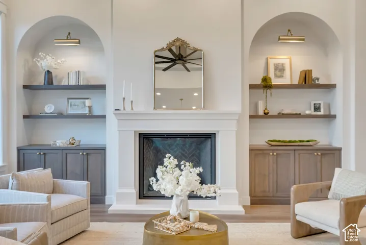Fireplace featuring a custom mantle and herringbone-patterned firebox interior, flanked by twin arched niches with wood-finish shelving, lower storage cabinetry, and integrated picture lighting