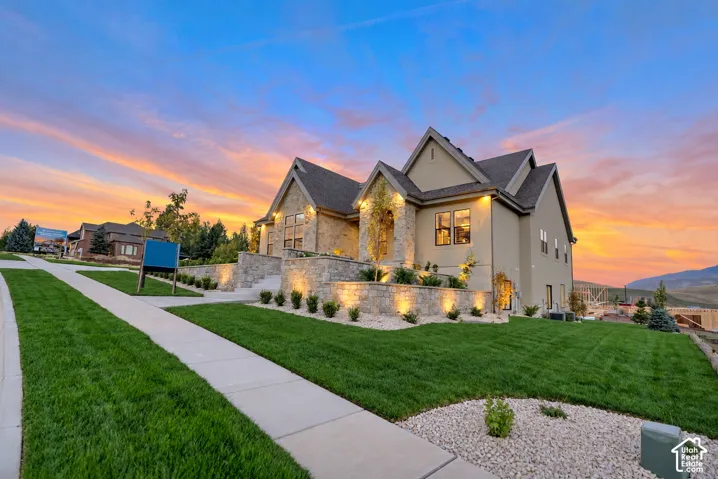 Exterior elevation featuring stone veneer siding, multi-gabled roofline, concrete retaining wall, and manicured landscaping