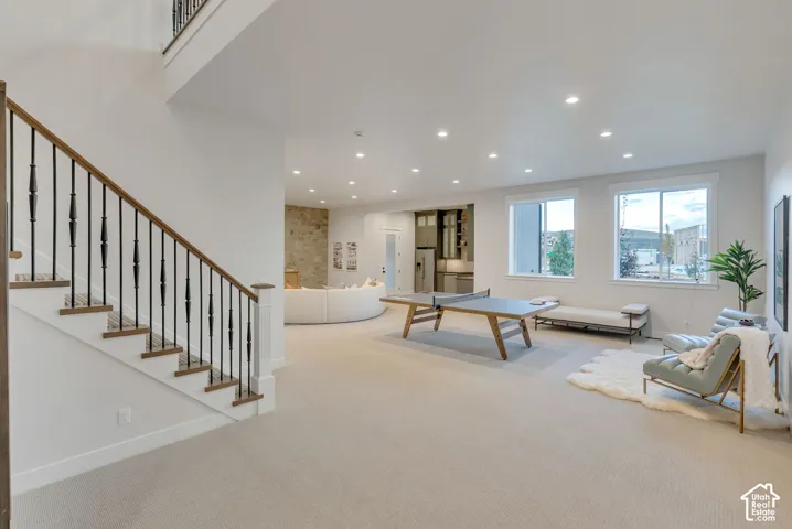 Open floor plan featuring recessed lighting, a stone-accented wall, and a staircase with a wooden handrail and black metal balusters