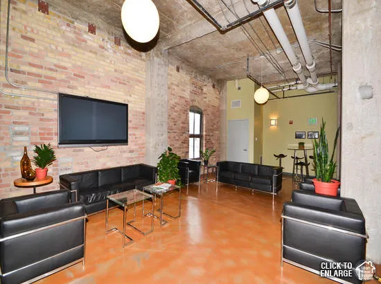 Industrial-style interior featuring exposed brick walls, high concrete ceilings, polished concrete flooring, and exposed ductwork
