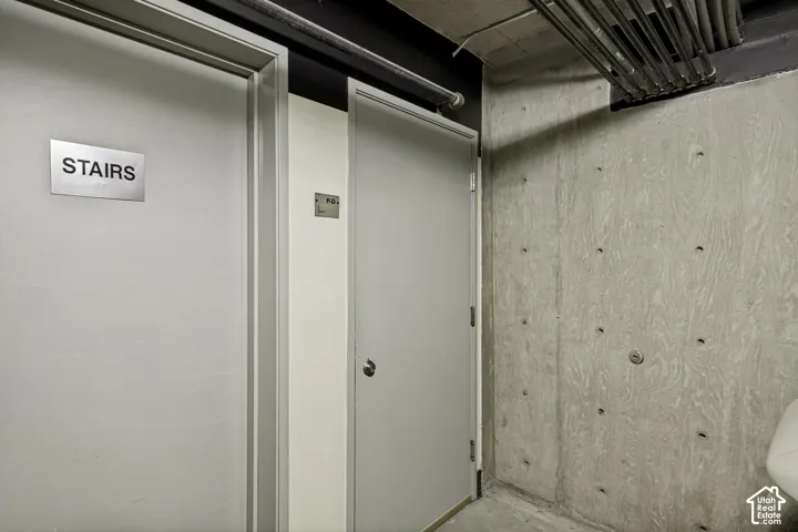 Exposed concrete wall with structural ties, industrial-style exposed ceiling conduit, and dual steel-frame doors