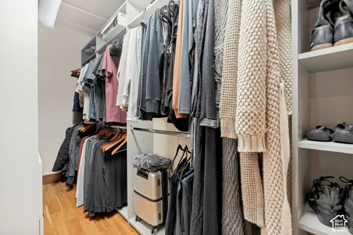 Custom walk-in closet featuring floor-to-ceiling white shelving, integrated hanging rods, and wood-finish flooring