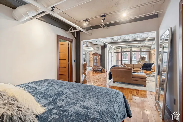 Industrial-style interior featuring exposed concrete ceilings, ductwork, wood-finish flooring, and multi-panel interior wooden doors