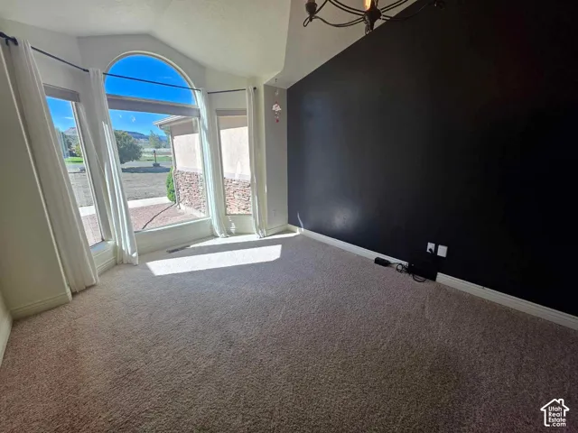 Vaulted ceilings with a geometric chandelier, expansive bay window, and a prominent accent wall