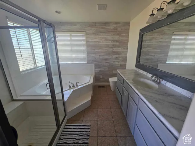 Bathroom featuring a soaking tub, glass-enclosed shower, dual-sink vanity with patterned countertop, and wood-finish wall paneling
