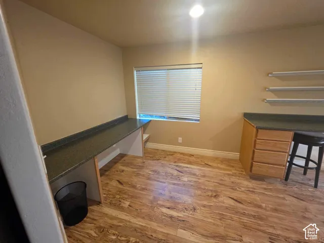 Built-in wood cabinetry, integrated stone-finish countertops, wood-finish flooring, and wall-mounted shelving