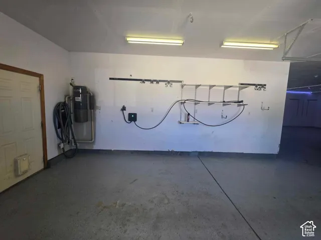 Garage featuring an epoxy-coated floor, central vacuum system, wall-mounted storage shelving, and dual overhead fluorescent lighting fixtures