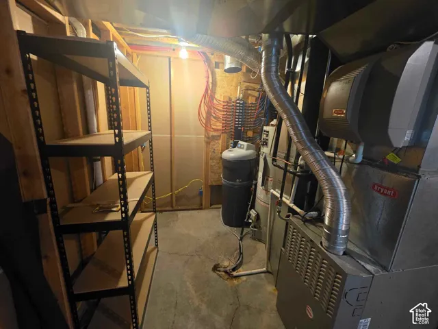 Utility area featuring a Bryant furnace, water softener, and a central manifold plumbing system with exposed framing