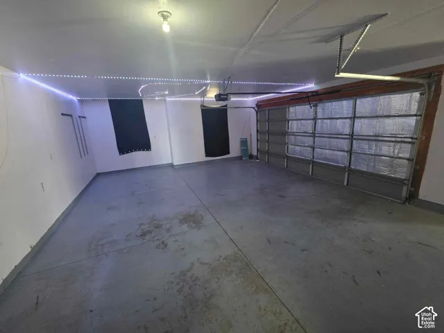 Multi-car garage featuring a sectional metal overhead door, concrete flooring, and ceiling-mounted LED perimeter lighting