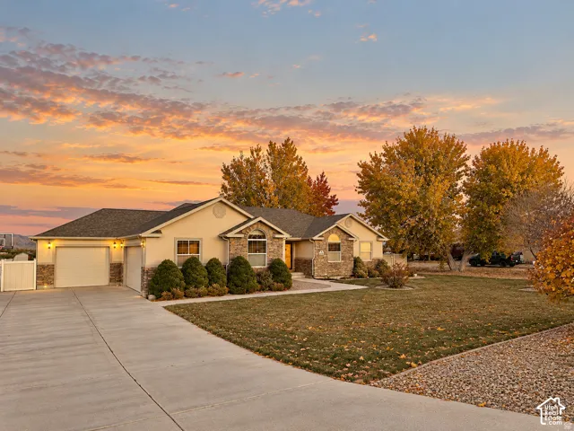 Stucco exterior featuring stone veneer accents, an attached three-car garage, concrete driveway, and arched window detailing