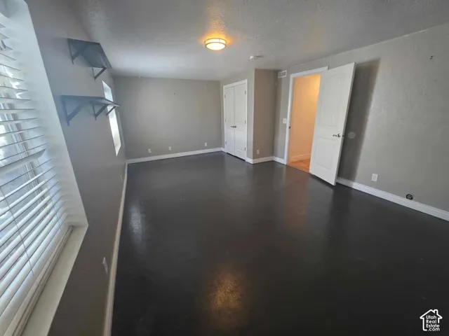 Room featuring dark-toned flooring, two built-in wall shelves, a multi-panel door closet, and a ceiling-mounted light fixture