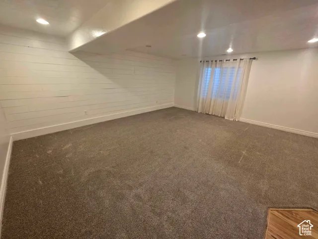 Interior space featuring horizontal shiplap wall paneling, recessed lighting, and wall-to-wall carpeting
