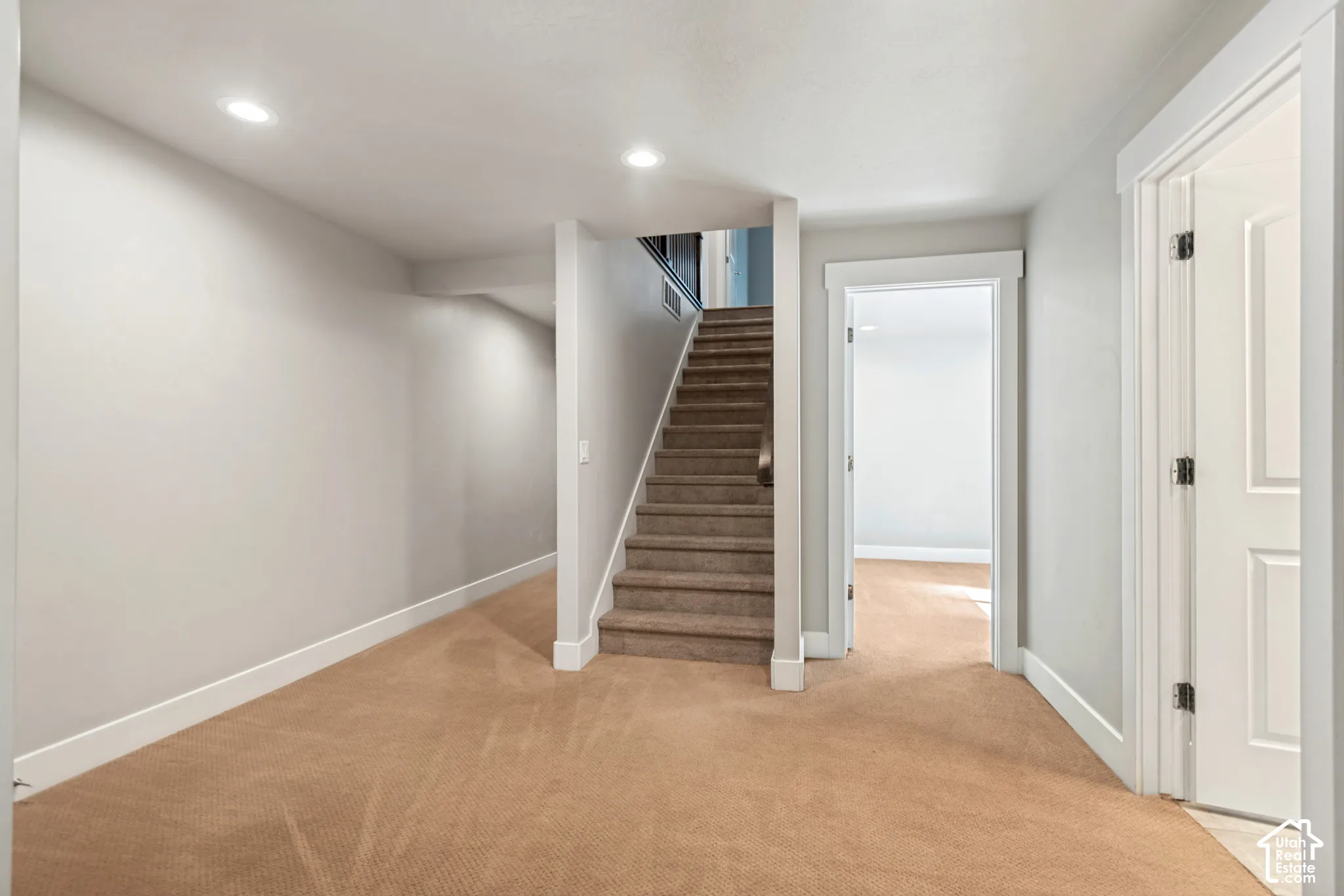 Carpeted interior featuring recessed lighting, a staircase with carpeting, and paneled doors with casing