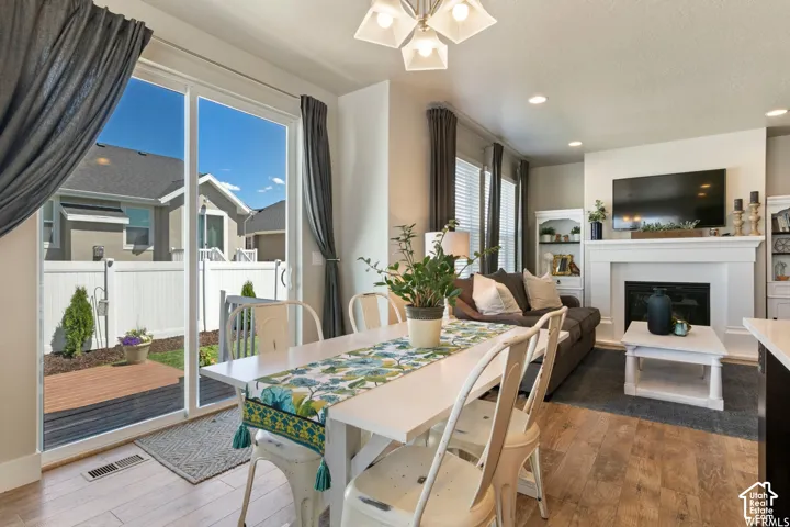 Sliding glass door, wood-finish flooring, built-in fireplace with white mantel, built-in shelving, and recessed lighting