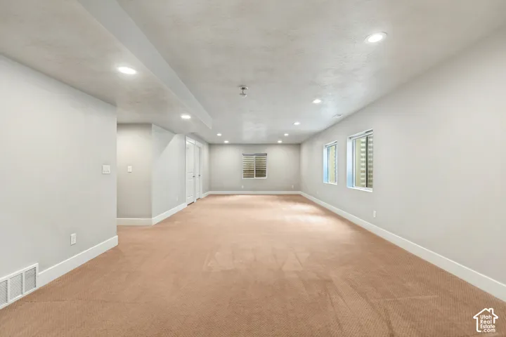 Open floor plan featuring neutral wall tones, recessed lighting, wall-to-wall carpeting, and multiple windows