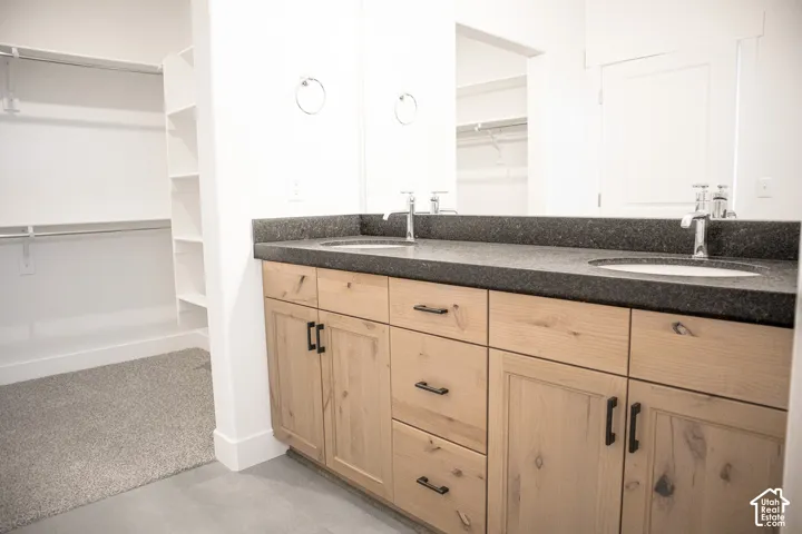 Primary bath with dual sinks, stained wood cabinets and granite slab countertops.
