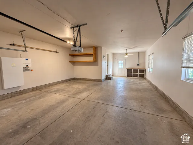 Multi-car garage featuring concrete flooring, built-in wooden shelving, a ceiling-mounted light fixture, and a white exterior door with window panes