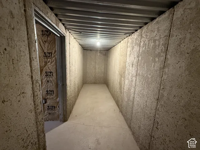 Utility storage space featuring concrete foundation walls, a concrete floor, and a corrugated metal ceiling