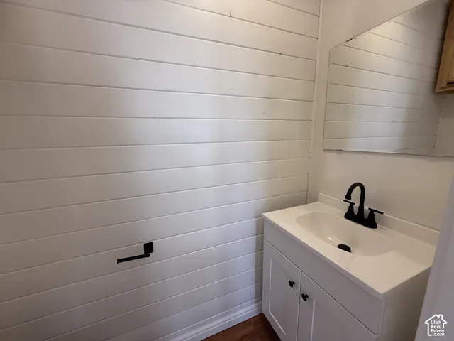Shiplap wall paneling, white vanity cabinet with integrated basin, matte black faucet, and wall-mounted mirror