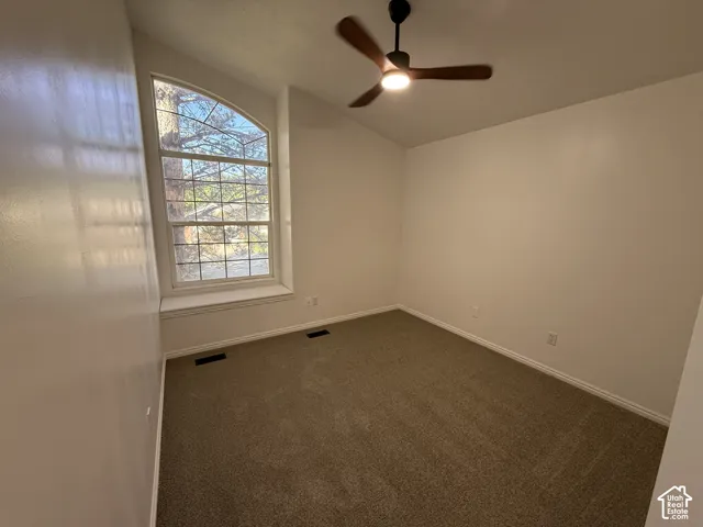 Vaulted ceiling featuring an arched window, integrated window seat, and an attached three-blade ceiling fan with light fixture