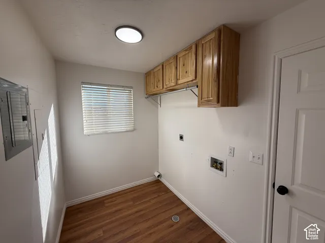 Utility area featuring wood-finish flooring, wall-mounted natural wood cabinetry, a hanging rod, and a window with blinds