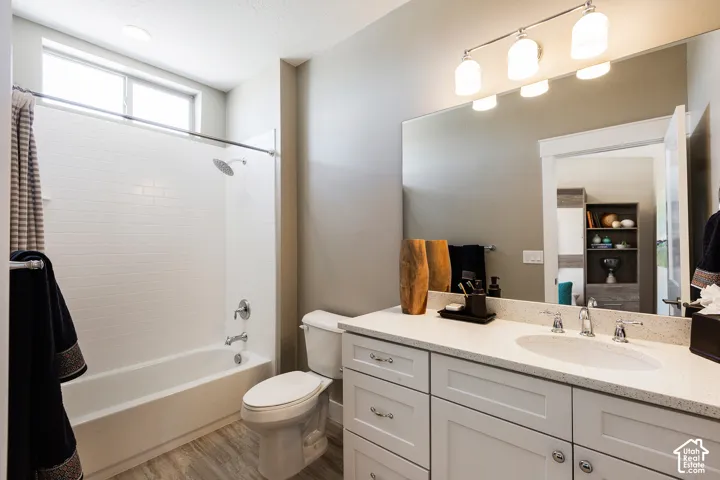 Bathroom featuring a vanity with white cabinetry, a neutral stone-composite countertop, an undermount sink, a full-width mirror, and a tub-shower combination with white subway-style tile surround