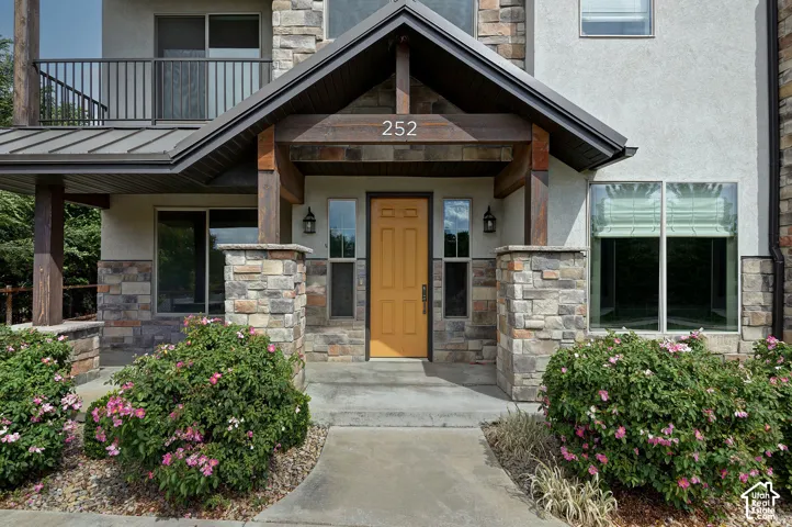Exterior facade featuring a gabled entryway, stone masonry, wood-timber accents, and a concrete front walkway