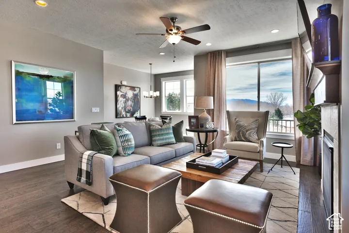Wood-finish flooring, ceiling fan with integrated lighting, recessed lighting, and a fireplace with a mantel
