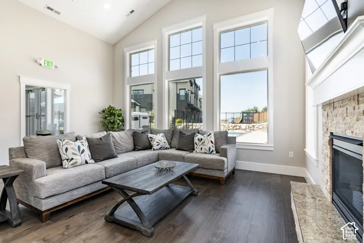 Vaulted ceilings, tall windows with transoms, stone-surround fireplace with a hearth, and wood-finish flooring