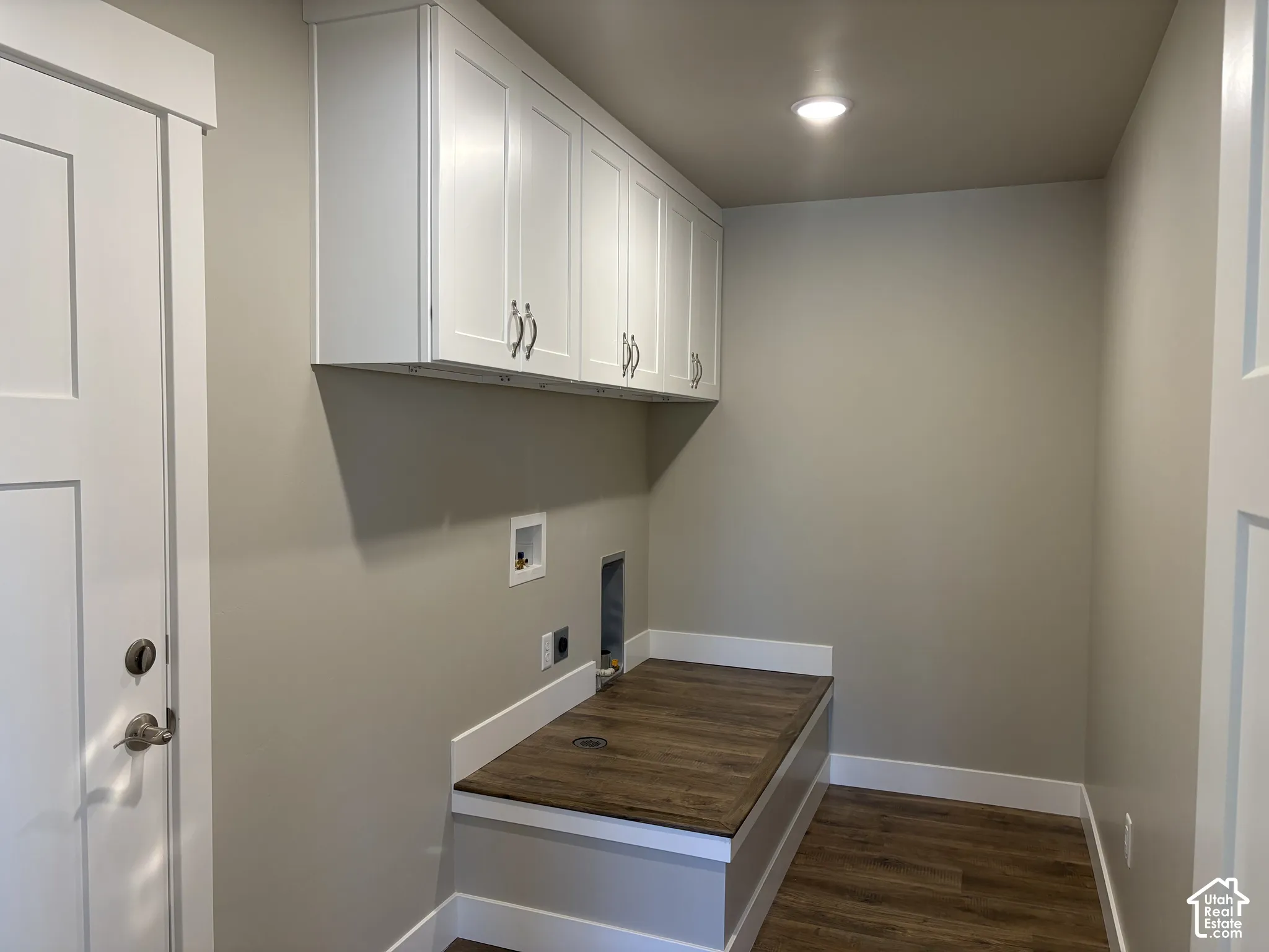 Laundry area featuring white shaker-style wall cabinets, wood-finish countertop surfacing, and recessed ceiling lighting