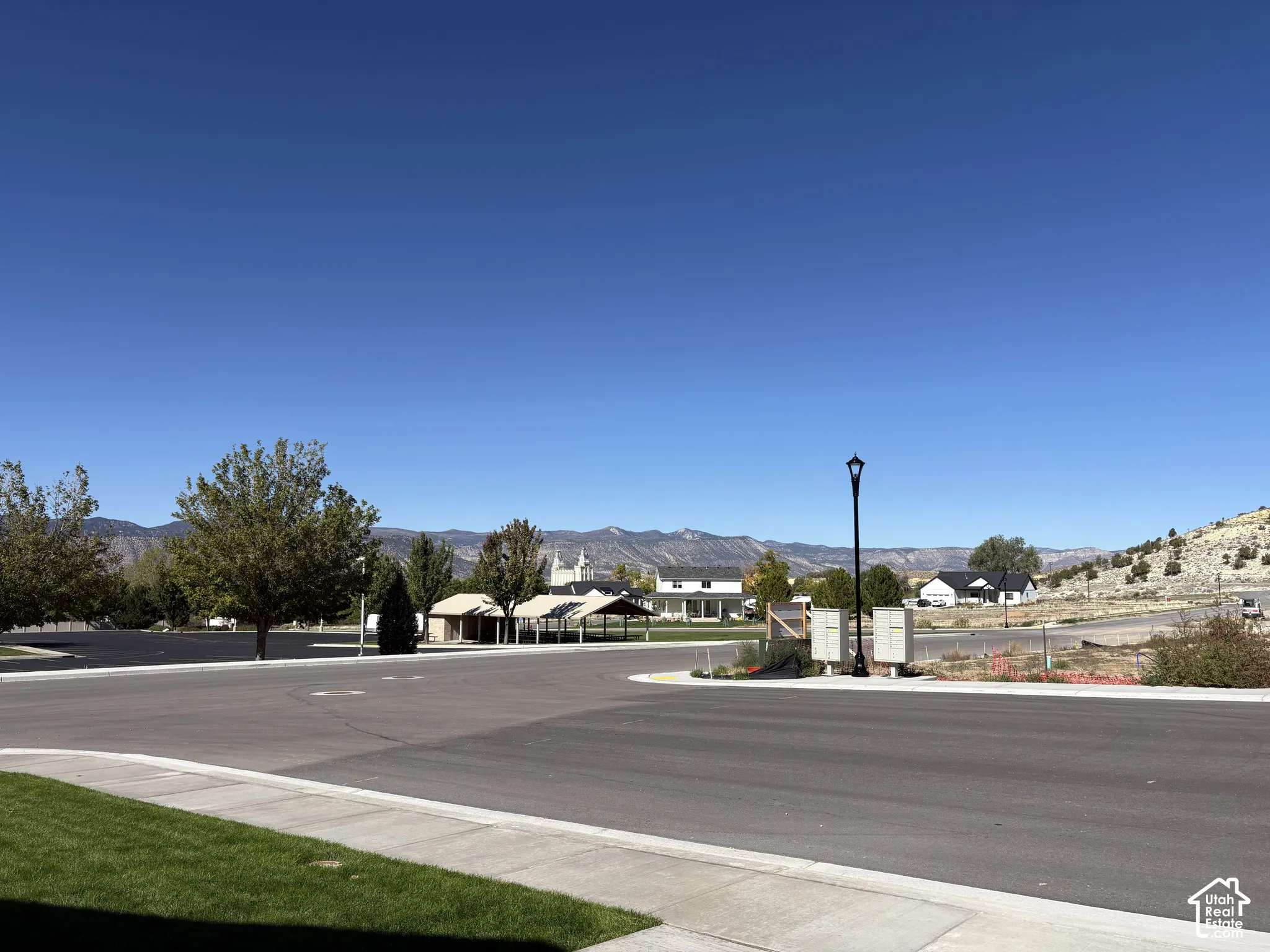 Paved street featuring curb-lined sidewalks, a decorative street lamp, and mountain scenery