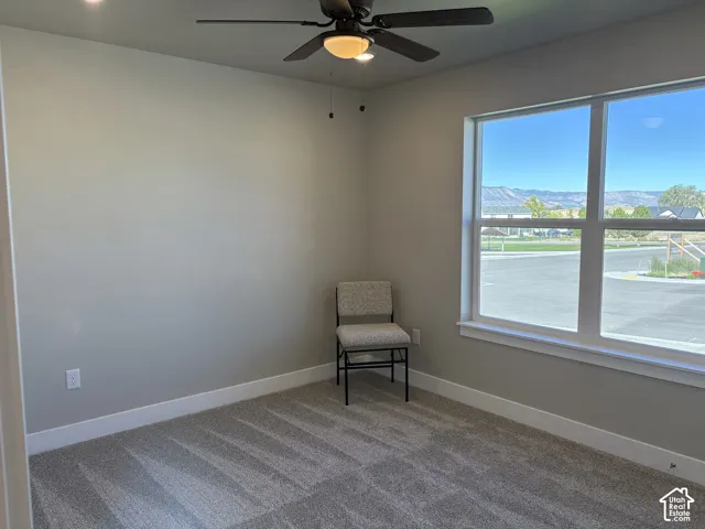 Neutral-toned walls, carpeted flooring, large picture window with mountain backdrop, and ceiling fan with integrated light fixture