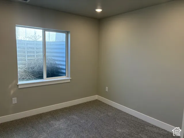 Neutral-toned interior space featuring wall-to-wall carpeting, recessed ceiling lighting, and a single-pane sliding window